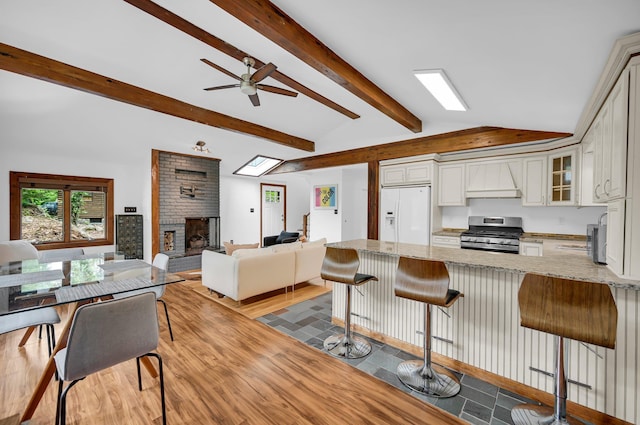 39 Cliff Rd, Greenwood Lake, NY 10925 - kitchen with stainless steel stove, white refrigerator with ice dispenser, open floor plan, a peninsula, and a brick fireplace