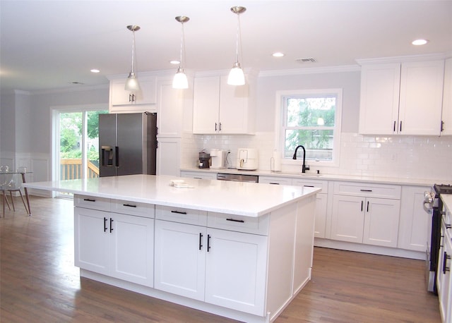8 W Narcissus Rd, Mastic Beach, NY 11951 - kitchen featuring appliances with stainless steel finishes, crown molding, a center island, white cabinets, and light countertops