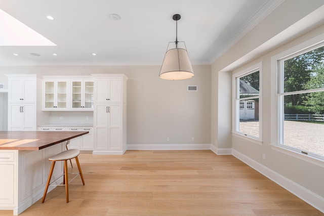 1750 Mount Beulah Ave, Southold, NY 11971 - kitchen with wood counters, white cabinetry, glass insert cabinets, decorative light fixtures, and ornamental molding