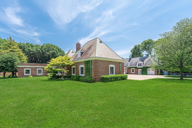 1750 Mount Beulah Ave, Southold, NY 11971 - rear view of house with a chimney, concrete driveway, a yard, and brick siding