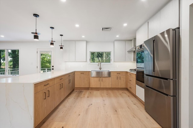 8 Junard Dr, Roslyn, NY 11576 - kitchen with freestanding refrigerator, a peninsula, light brown cabinets, light wood-type flooring, and light stone countertops