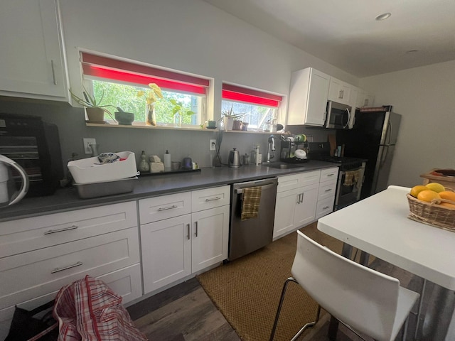 130 Van Dyke St, Brooklyn, NY 11231 - kitchen featuring stainless steel appliances, a sink, white cabinetry, dark wood-style flooring, and dark countertops