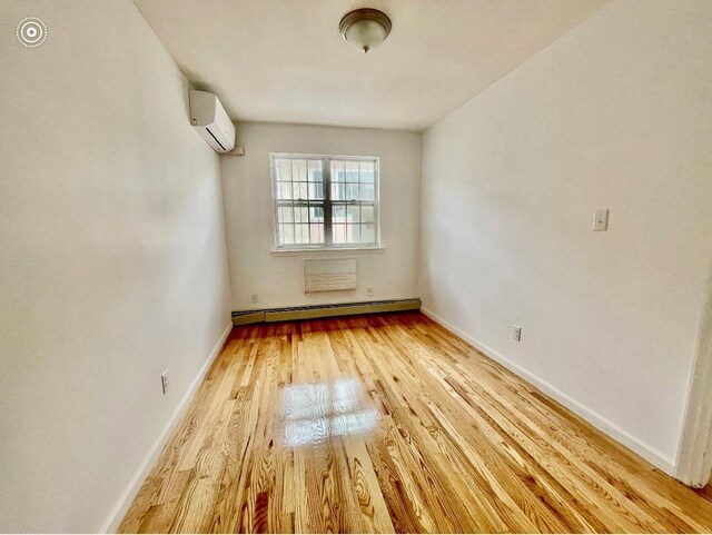 132-06 57th Rd, Flushing, NY 11355 - unfurnished room with a wall mounted AC, a baseboard heating unit, light wood-style floors, and baseboards