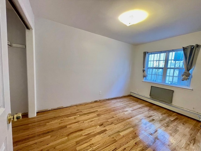 132-06 57th Rd, Flushing, NY 11355 - unfurnished bedroom with light wood-style floors and a baseboard radiator