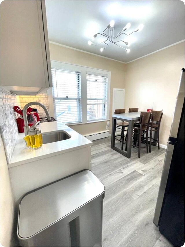 100-15 Ascan Ave, Forest Hills, NY 11375 - kitchen featuring a baseboard heating unit, decorative backsplash, a chandelier, light wood finished floors, and light countertops