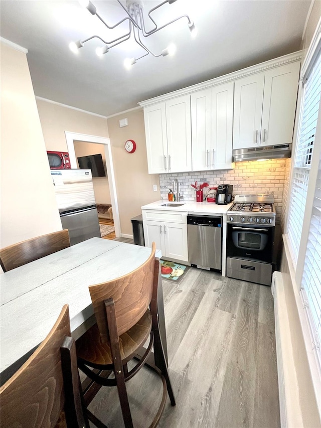 100-15 Ascan Ave, Forest Hills, NY 11375 - kitchen featuring appliances with stainless steel finishes, under cabinet range hood, a chandelier, light wood-style floors, and tasteful backsplash