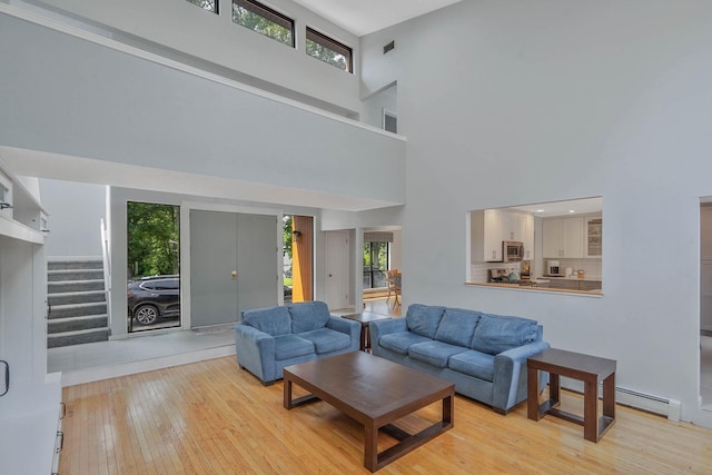318 Sheep Pasture Rd, East Setauket, NY 11733 - living room featuring a high ceiling, a baseboard heating unit, plenty of natural light, and hardwood / wood-style floors