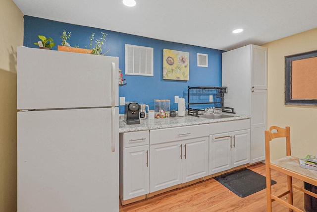 318 Sheep Pasture Rd, East Setauket, NY 11733 - kitchen with freestanding refrigerator, light wood-style floors, white cabinets, light countertops, and recessed lighting