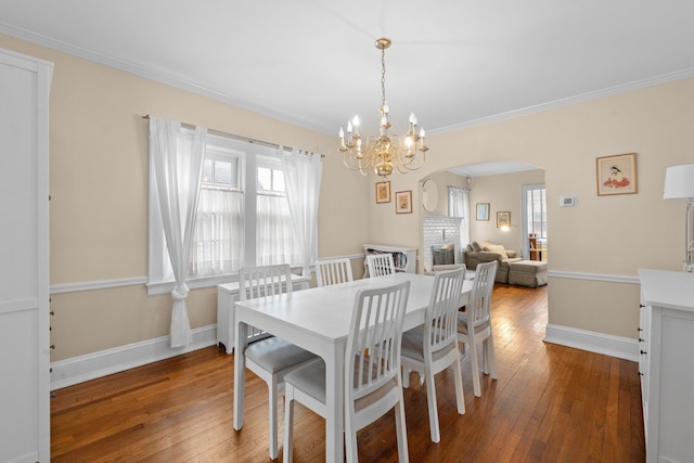 206 Brower Ave, Rockville Centre, NY 11570 - dining area with arched walkways, healthy amount of natural light, a chandelier, ornamental molding, and hardwood / wood-style floors
