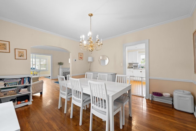 206 Brower Ave, Rockville Centre, NY 11570 - dining area featuring arched walkways, a chandelier, ornamental molding, and hardwood / wood-style flooring