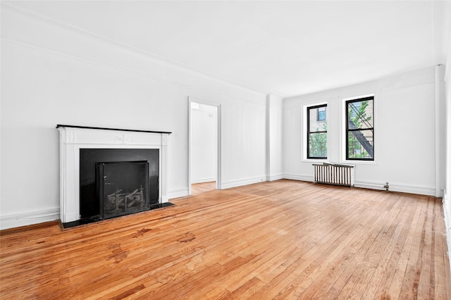 43 Calton Rd Unit 4J, New Rochelle, NY 10804 - unfurnished living room featuring radiator heating unit, hardwood / wood-style flooring, and a fireplace with flush hearth
