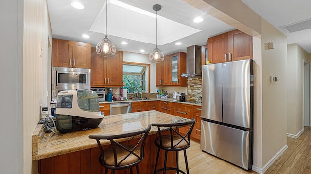 6 Sycamore Pl, Smithtown, NY 11787 - kitchen featuring stainless steel appliances, wall chimney exhaust hood, light wood finished floors, a kitchen breakfast bar, and recessed lighting