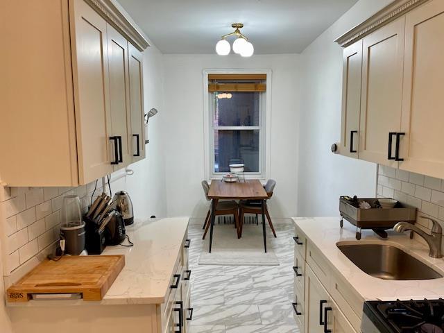 72-17 34th Ave Unit 1H, Jackson Heights, NY 11372 - kitchen with a sink, backsplash, light marble finish floors, light stone countertops, and range
