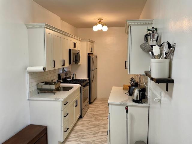 72-17 34th Ave Unit 1H, Jackson Heights, NY 11372 - kitchen with stainless steel appliances, light marble finish flooring, light countertops, tasteful backsplash, and a sink