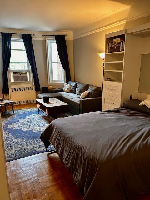 72-17 34th Ave Unit 1H, Jackson Heights, NY 11372 - bedroom with radiator heating unit, cooling unit, and wood finished floors
