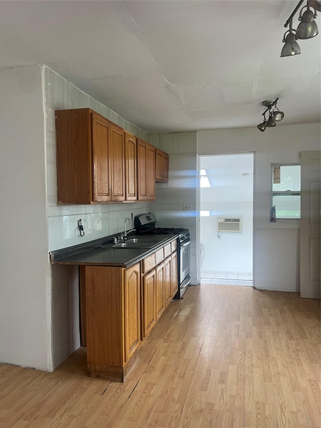20 Rollin Ln, Brentwood, NY 11717 - kitchen featuring stainless steel gas range, a sink, dark countertops, brown cabinetry, and light wood-type flooring