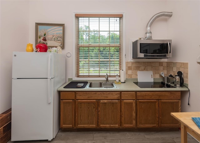 6807 State Route 42, Woodbourne, NY 12788 - kitchen with freestanding refrigerator, stainless steel microwave, black electric stovetop, and brown cabinetry