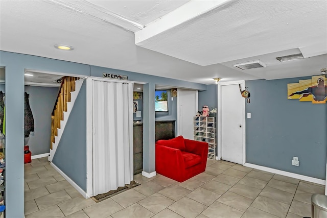 90 Charles St, Lynbrook, NY 11563 - finished basement with stairs, baseboards, a textured ceiling, and tile patterned flooring