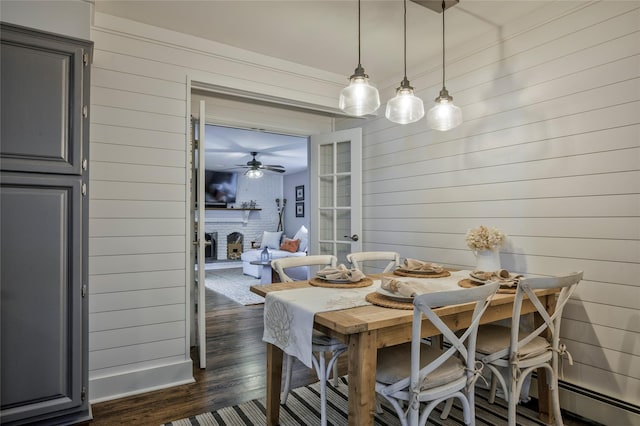 25 Jackwill Rd, East Patchogue, NY 11772 - dining room featuring wooden walls, a brick fireplace, dark wood-style floors, ceiling fan, and baseboard heating