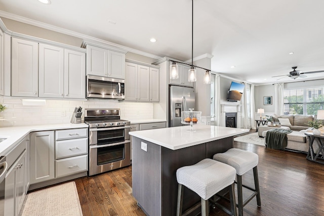35 Laurel Cir, Goshen, NY 10924 - kitchen featuring stainless steel appliances, ornamental molding, dark wood-style floors, a kitchen bar, and backsplash