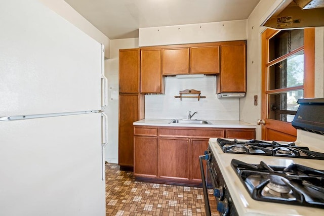 628 8th Ave, New Hyde Park, NY 11040 - kitchen with freestanding refrigerator, gas stove, light countertops, brown cabinetry, and tasteful backsplash