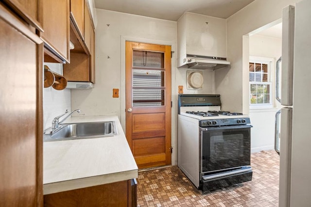 628 8th Ave, New Hyde Park, NY 11040 - kitchen with range with gas cooktop, under cabinet range hood, freestanding refrigerator, light countertops, and brown cabinets