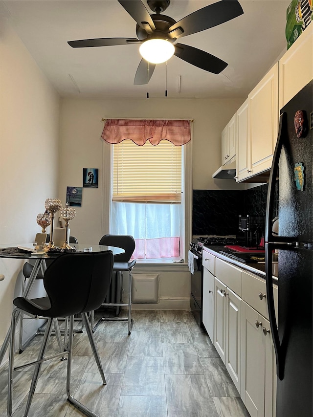 39-82 65th Pl Unit 4F, Woodside, NY 11377 - kitchen featuring black appliances, ceiling fan, white cabinets, under cabinet range hood, and dark countertops