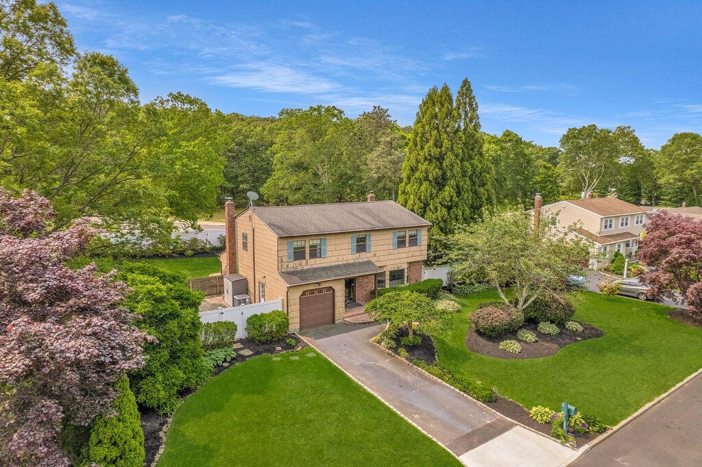 8 Astro Ct, Holtsville, NY 11742 - view of front facade with a garage, concrete driveway, brick siding, a chimney, and a wooded view