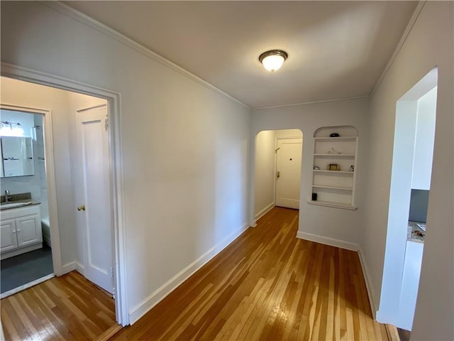 90 Bryant Ave Unit 5B-E, White Plains, NY 10605 - hall featuring light wood-style flooring, a sink, baseboards, arched walkways, and crown molding
