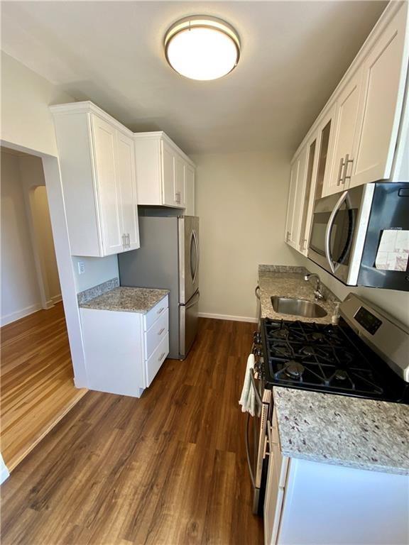 90 Bryant Ave Unit 5B-E, White Plains, NY 10605 - kitchen with appliances with stainless steel finishes, a sink, dark wood finished floors, baseboards, and white cabinets