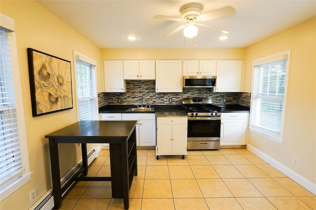 56 Academy St, Patchogue, NY 11772 - kitchen featuring stainless steel appliances, dark countertops, decorative backsplash, ceiling fan, and a baseboard heating unit