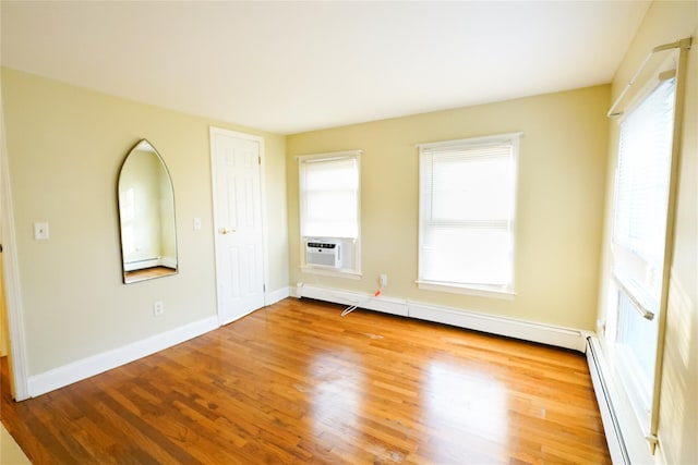 56 Academy St, Patchogue, NY 11772 - empty room with wood finished floors, a baseboard heating unit, plenty of natural light, and a baseboard radiator