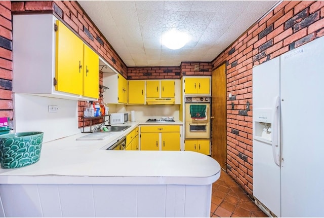 5883 57th Rd, Maspeth, NY 11378 - kitchen featuring white appliances, brick wall, yellow cabinetry, light countertops, and under cabinet range hood