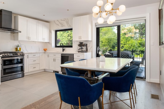 1363 Kearney Ave, Bronx, NY 10465 - kitchen with wall chimney range hood, appliances with stainless steel finishes, a chandelier, light countertops, and white cabinetry