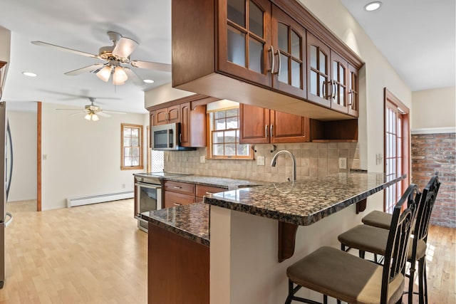206 Lower Sheep Pasture Rd, Setauket, NY 11733 - kitchen featuring appliances with stainless steel finishes, a baseboard radiator, a peninsula, ceiling fan, and glass insert cabinets