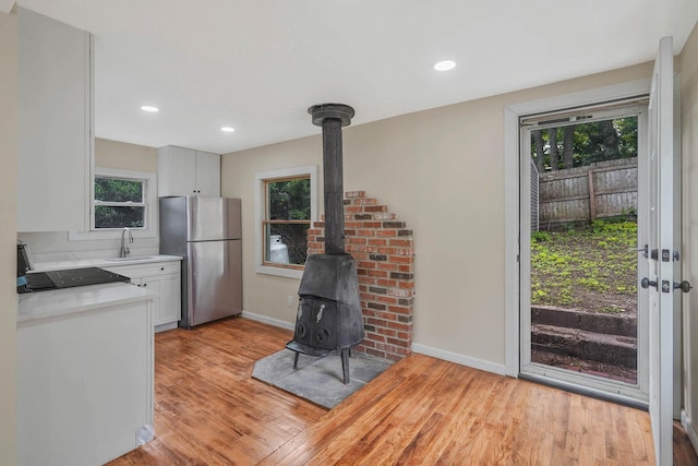18 Port Jefferson Rd, Sound Beach, NY 11789 - kitchen with freestanding refrigerator, a wood stove, light countertops, light wood finished floors, and white cabinetry