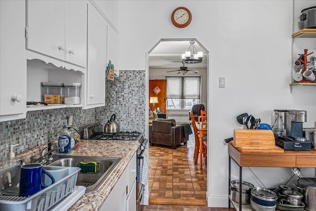 10712 Sutter Ave, Ozone Park, NY 11417 - kitchen featuring gas range, brick patterned floors, white cabinets, and arched walkways