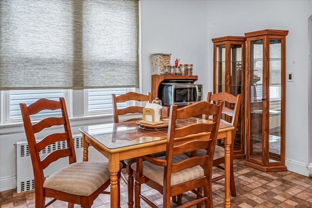 10712 Sutter Ave, Ozone Park, NY 11417 - dining area featuring radiator, baseboards, and brick patterned floors