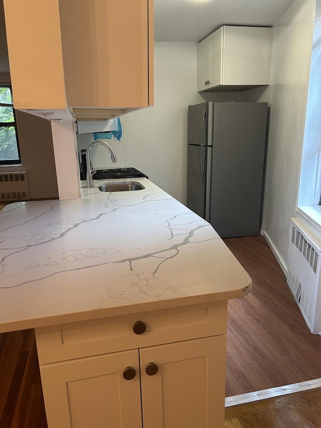 43-25 Douglaston Pkwy Unit 2D, Douglaston, NY 11363 - kitchen with freestanding refrigerator, radiator, dark wood-style flooring, light stone counters, and white cabinetry