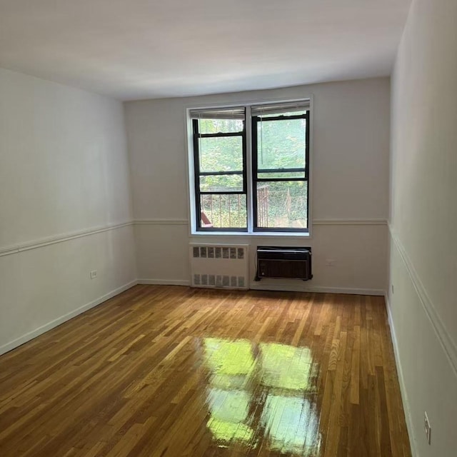 43-25 Douglaston Pkwy Unit 2D, Douglaston, NY 11363 - empty room with radiator, hardwood / wood-style floors, and a wall unit AC