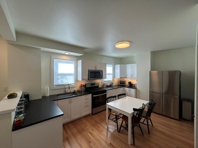 22 Spring St, Port Chester, NY 10573 - kitchen with appliances with stainless steel finishes, a sink, light wood finished floors, and white cabinets