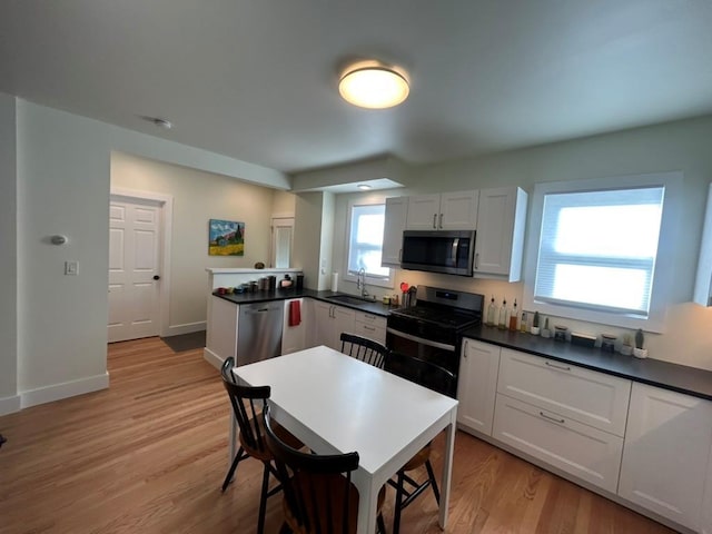 22 Spring St, Port Chester, NY 10573 - kitchen featuring stainless steel appliances, a sink, light wood-type flooring, dark countertops, and baseboards
