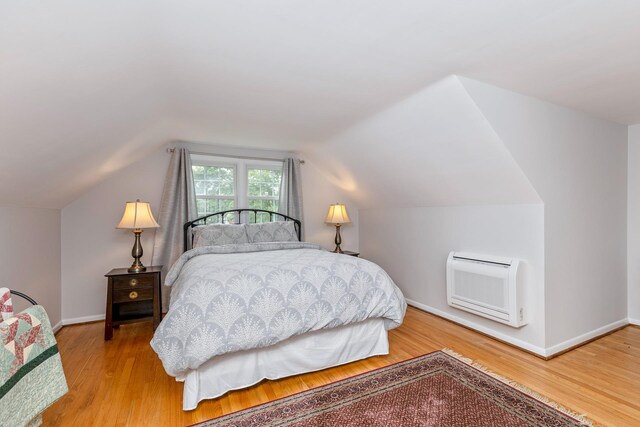 2 The Spout, Smithtown, NY 11787 - bedroom with wood finished floors, vaulted ceiling, and heating unit