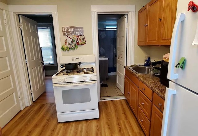 77 Carroll St, Poughkeepsie, NY 12601 - kitchen with white appliances, light wood-type flooring, brown cabinets, and dark countertops