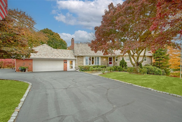 25 Fountain Dr, Valhalla, NY 10595 - ranch-style home featuring a chimney, an attached garage, a front yard, asphalt driveway, and stone siding