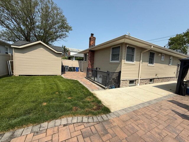 1803 Front St, East Meadow, NY 11554 - rear view of house with a chimney, a patio, and an outdoor structure