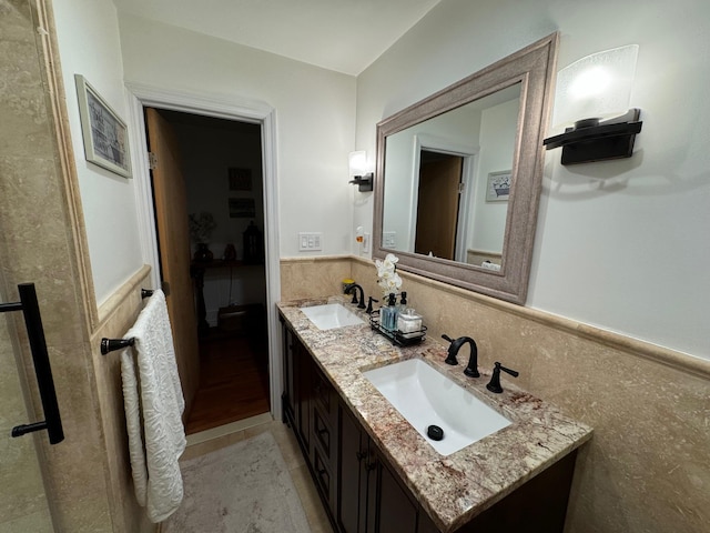 1803 Front St, East Meadow, NY 11554 - bathroom with tile walls, a wainscoted wall, double vanity, and tile patterned floors