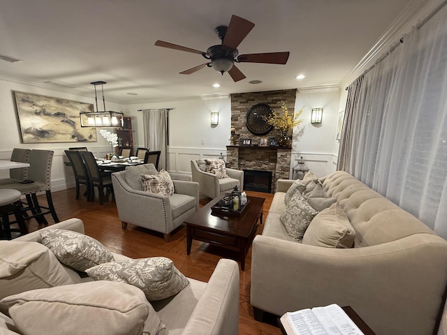 1803 Front St, East Meadow, NY 11554 - living area with crown molding, ceiling fan, a decorative wall, a stone fireplace, and a wainscoted wall