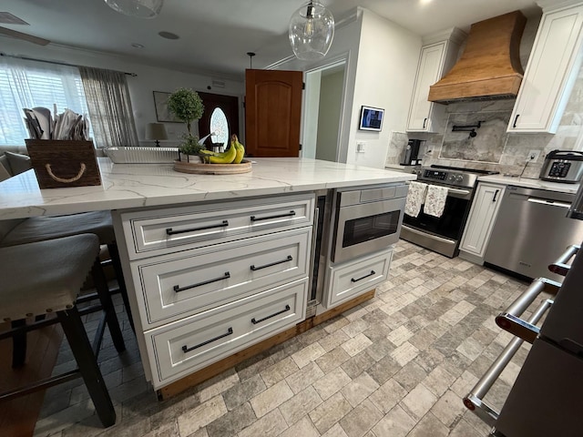 1803 Front St, East Meadow, NY 11554 - kitchen with premium range hood, appliances with stainless steel finishes, tasteful backsplash, white cabinetry, and light stone countertops