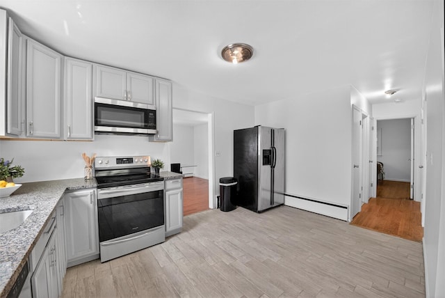 26 Helena Ave, Mohegan Lake, NY 10547 - kitchen with appliances with stainless steel finishes, baseboard heating, light wood-style flooring, and light stone counters
